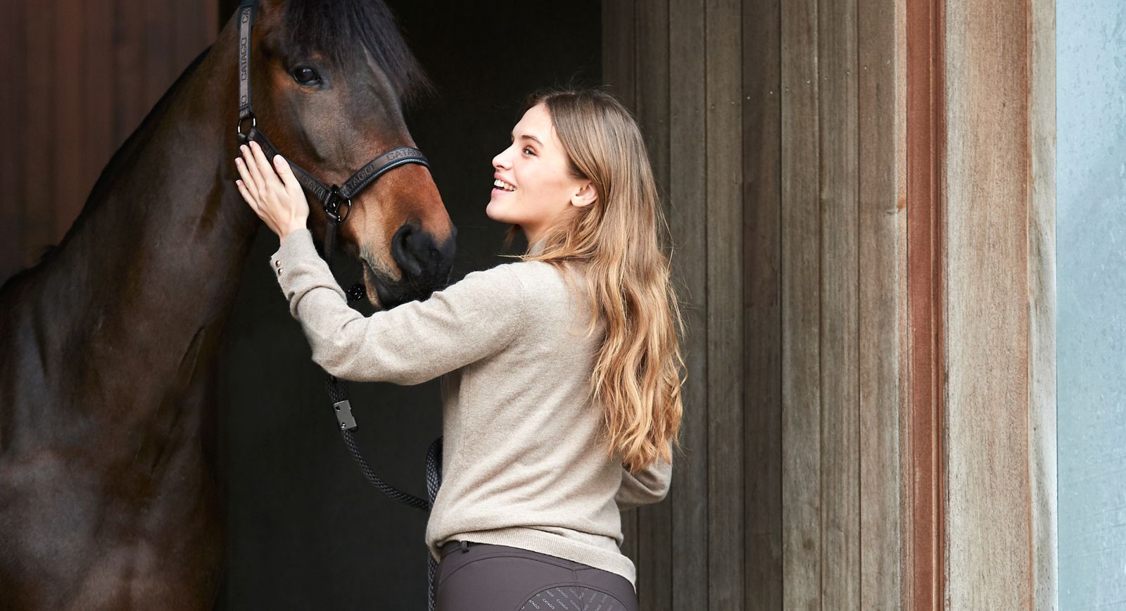 Woman petting a horse in a stable doorway