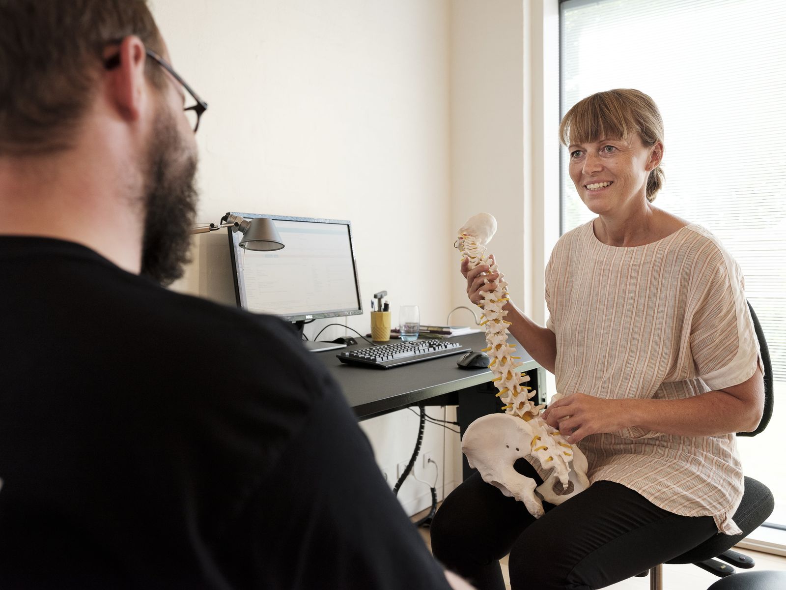 Chiropractor showing a patient a spine model in a clinic office